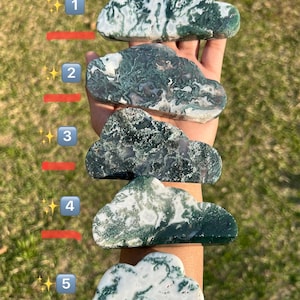 May include: Five green and white agate cloud shaped stones of varying sizes. The stones are arranged vertically on a person's arm, with the largest stone at the top and the smallest stone at the bottom.