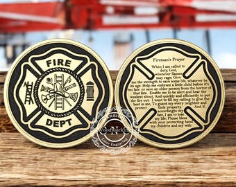 May include: Two gold-colored metal coins with a black background. One coin features a firefighter's helmet, axe, ladder, and fire hydrant inside a black fire department cross with the words "FIRE DEPT". The other coin features the "Fireman's Prayer" text.