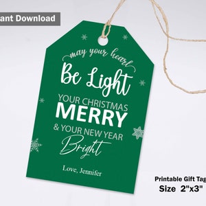 May include: A green gift tag with white text that reads "may your heart Be Light YOUR CHRISTMAS MERRY & YOUR NEW YEAR Bright". Includes snowflakes and the text "Love, Jennifer". The tag is 2" x 3" and has a string.