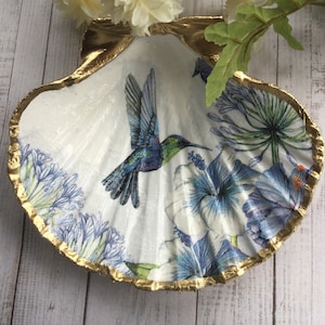 May include: A white seashell dish with a gold rim, featuring a blue and green hummingbird and floral designs.