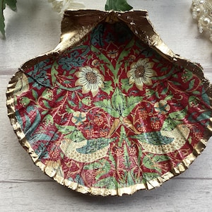 May include: A gold-rimmed seashell dish with a red, green and white floral pattern featuring birds.