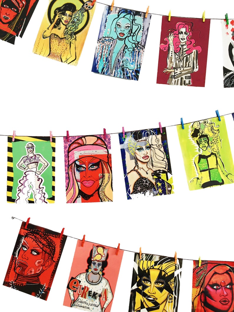 May include: A collection of colorful illustrations of drag queens, each with a unique style and personality. The illustrations are displayed on a white background and are hung with clothespins on a string.