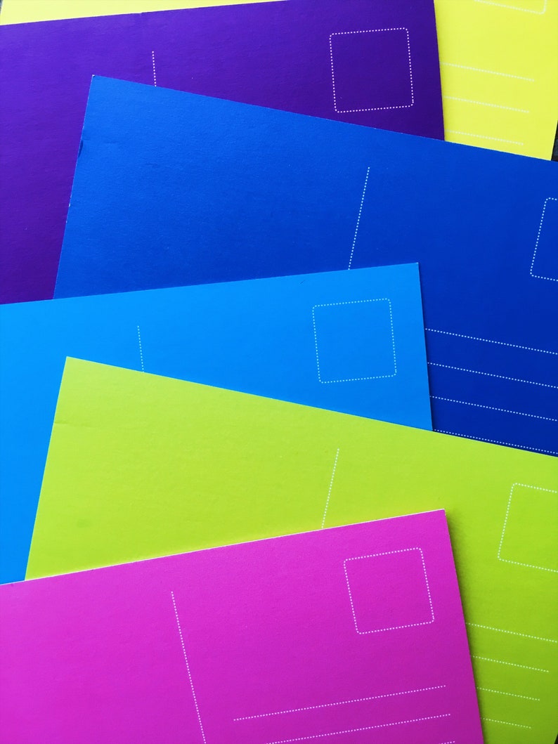 May include: A stack of colorful postcards with white dotted lines and a blank space for an address. The postcards are in shades of purple, blue, green, and pink.