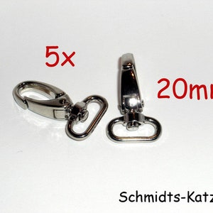 Può includere: Cinque moschettoni girevoli in metallo argentato, ciascuno lungo 20 mm. I moschettoni sono progettati per essere fissati a cinghie, borse o altri accessori.