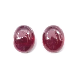 May include: Two round, red gemstones with a smooth, polished surface.