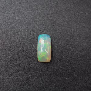 May include: A white opal gemstone with green and blue flashes of color.