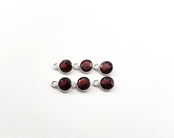 May include: Six silver-toned gemstone connectors with red-brown round gemstones. The connectors have two loops on each side.