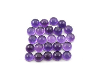 Puede incluir: Colección de veinticuatro gemas de amatista redondas y pulidas. Las piedras, de color púrpura intenso, están dispuestas en un patrón rectangular sobre un fondo blanco. Adecuadas para la fabricación de joyas o coleccionar. Cada piedra mide aproximadamente 1 cm de diámetro.