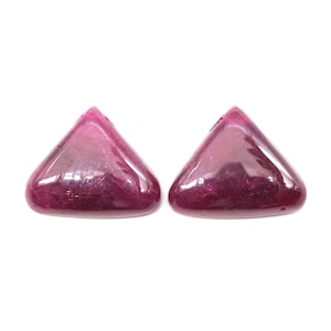 May include: Two triangular shaped gemstones with a deep pink color. The gemstones are smooth and shiny.
