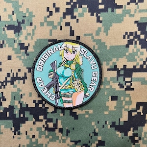 May include: A round, embroidered patch with a light blue background. The patch features a cartoon anime-style woman holding a rifle. The text "ORIGINAL SLAVU GEAR" is written in a circle around the woman.
