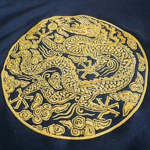 Op de afbeelding: Een ronde geborduurde patch met een gouden draakontwerp op een donkerblauwe achtergrond. De draak wordt omringd door gestileerde wolken en andere decoratieve elementen.