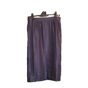 Puede incluir: Una falda de color morado oscuro hecha de una tela similar al lino. La falda tiene una silueta recta y un dobladillo ligeramente acampanado.