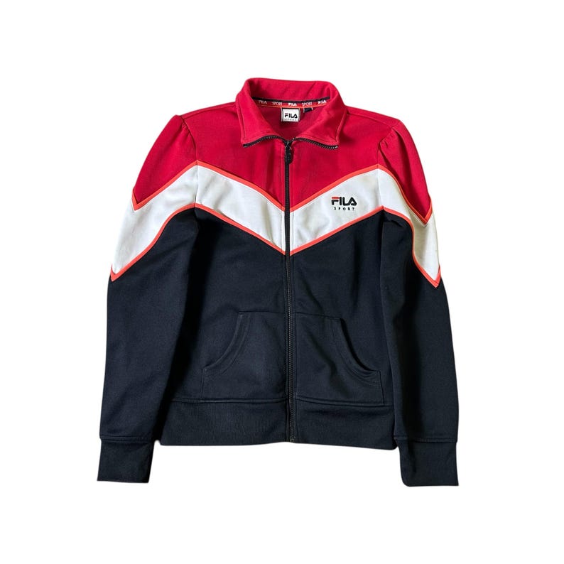K&ouml;nnte beinhalten: FILA-Trainingsjacke mit Rei&szlig;verschluss in Rot, Wei&szlig; und Marineblau. Die Jacke hat ein Zickzackmuster auf Brust und Schultern, mit dem FILA-Logo auf Brust und Kragen. Sie hat einen durchgehenden Rei&szlig;verschluss und zwei Vordertaschen.