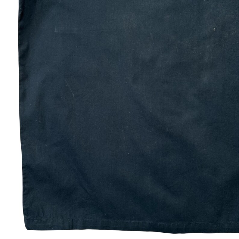 K&ouml;nnte beinhalten: Nahaufnahme eines dunkelmarineblauen Stoffes. Der Stoff hat ein leicht strukturiertes Aussehen mit subtilen Farbvariationen und einigen sichtbaren Knitterfalten. Das Bild ist gut beleuchtet und hebt die Details des Materials hervor.