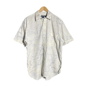 May include: A white short-sleeved button-down shirt with a nautical map print. The shirt has a blue label that says "Nautica" on the left side of the collar.