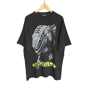 Könnte beinhalten: Schwarzes T-Shirt mit einem Grafikdruck eines Godzilla-ähnlichen Wesens mit dem Wort "Godzilla" in Gelb unter dem Wesen.