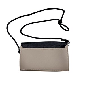 May include: A beige and black crossbody purse with a black adjustable strap. The purse has a flap closure and a silver accent.