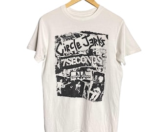 May include: White t-shirt with a black and white graphic print of the band Circle Jerks and 7 Seconds. The graphic includes the text "Circle Jerks Presents 7 Seconds Negative Approach".
