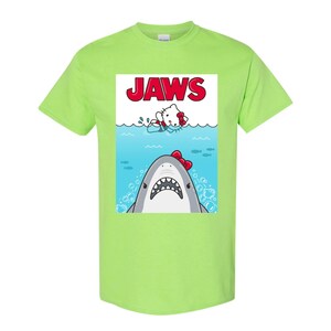 May include: A lime green t-shirt featuring a parody design of the movie "Jaws." The graphic shows a cartoon shark with a red bow tie and a cartoon cat in the water. The word "JAWS" is printed in red.