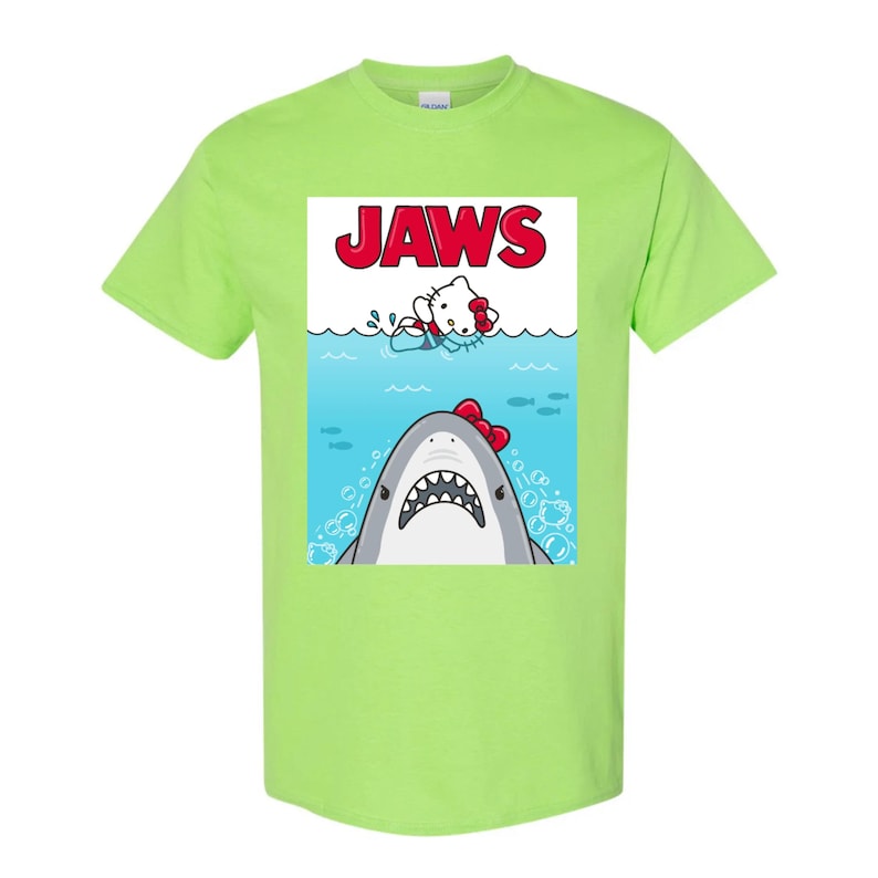 May include: A lime green t-shirt featuring a parody design of the movie "Jaws." The graphic shows a cartoon shark with a red bow tie and a cartoon cat in the water. The word "JAWS" is printed in red.