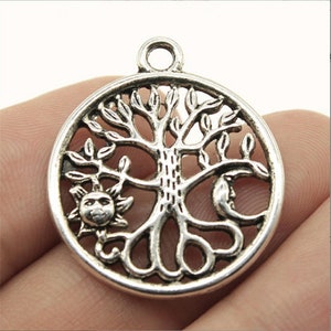 May include: Silver-toned metal pendant featuring a tree of life design with a sun and moon on either side. The pendant is circular and has a loop at the top for attaching to a chain.