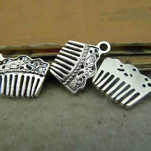 Könnte beinhalten: Drei silberfarbene Kamm-Anhänger mit verzierten Designs. Die Anhänger sind in Form eines Kamms mit einem dekorativen Rand.