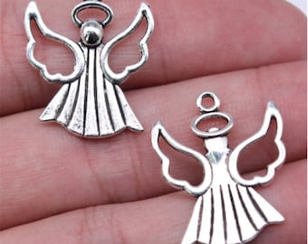 Puede incluir: Dos colgantes plateados con forma de ángel. Cada colgante presenta un ángel con alas extendidas, un halo y un vestido detallado. Los colgantes son de metal con un acabado envejecido y antiguo. Para la creación de joyas o manualidades.