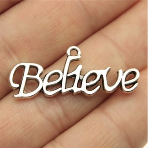 May include: Silver charm with the word "Believe" in a cursive font.
