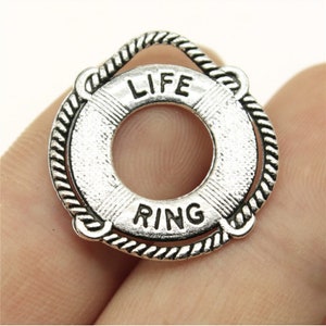 Op de afbeelding: Zilverkleurige metalen hanger in de vorm van een reddingsring met de tekst "LIFE RING" erop.