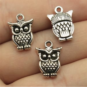 May include: Three silver owl charms with detailed designs. The owls have large eyes and are perched with their wings folded.