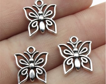 Pode incluir: Três pingentes de borboleta prateados com detalhes intrincados. Os pingentes são feitos de metal e têm um design delicado e adornado.