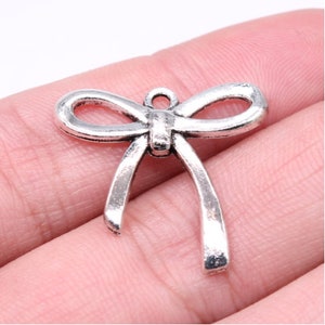 May include: Silver-toned metal bow charm with a loop for attaching to jewellery or crafts.
