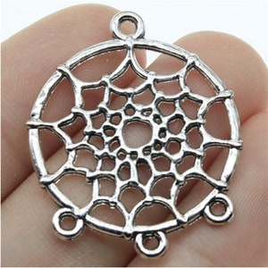 May include: Silver-toned metal dreamcatcher charm featuring a delicate web design and four loops for attaching to jewellery or other crafts.