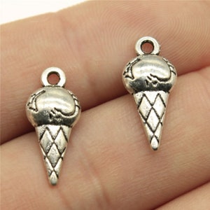 May include: Two silver charm pendants shaped like ice cream cones. The charms have a detailed design and are perfect for jewelry making.