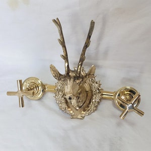 May include: Gold-toned faucet with a deer head design. The faucet has two cross-shaped handles.