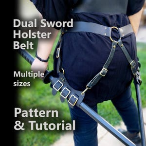 May include: Black leather dual sword holster belt with gold-coloured hardware. The belt has multiple straps and buckles for securing two swords. Text on the image reads "Dual Sword Holster Belt", "Multiple sizes", and "Pattern & Tutorial".