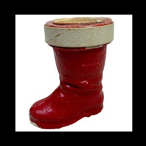 May include: A red boot-shaped container with a white and tan rim. The boot is a vibrant red color and appears to be made of a glossy material. The rim is a textured white with a tan interior. The container is likely a decorative item.