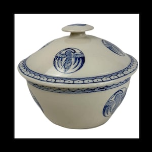 May include: A white ceramic lidded bowl with blue bird designs. The bowl has a rounded shape with a lid and a small knob. The rim and lid are decorated with a blue geometric pattern. The bird designs are repeated around the bowl.