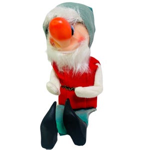 May include: A plush gnome doll with a red and white outfit, a white beard, and a green hat. The gnome has a large, red, bulbous nose.
