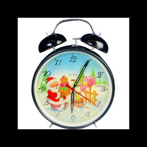 May include: A vintage black alarm clock with a festive Christmas-themed face. The clock face features Santa Claus holding gifts, a mailbox, and a snowy landscape. The clock has black bells and a metal frame.