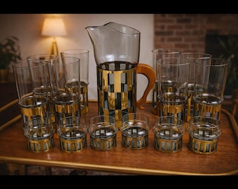 May include: A vintage glassware set featuring a clear glass pitcher with a gold and black checkered design and a wooden handle. The set includes tall drinking glasses and smaller glasses, all with gold accents. The glassware is arranged on a wooden serving tray.