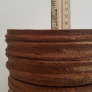 Pode incluir: Uma tigela de madeira com acabamento marrom e uma s&eacute;rie de an&eacute;is elevados ao redor da borda superior. A tigela tem um di&acirc;metro de aproximadamente 15 cm.
