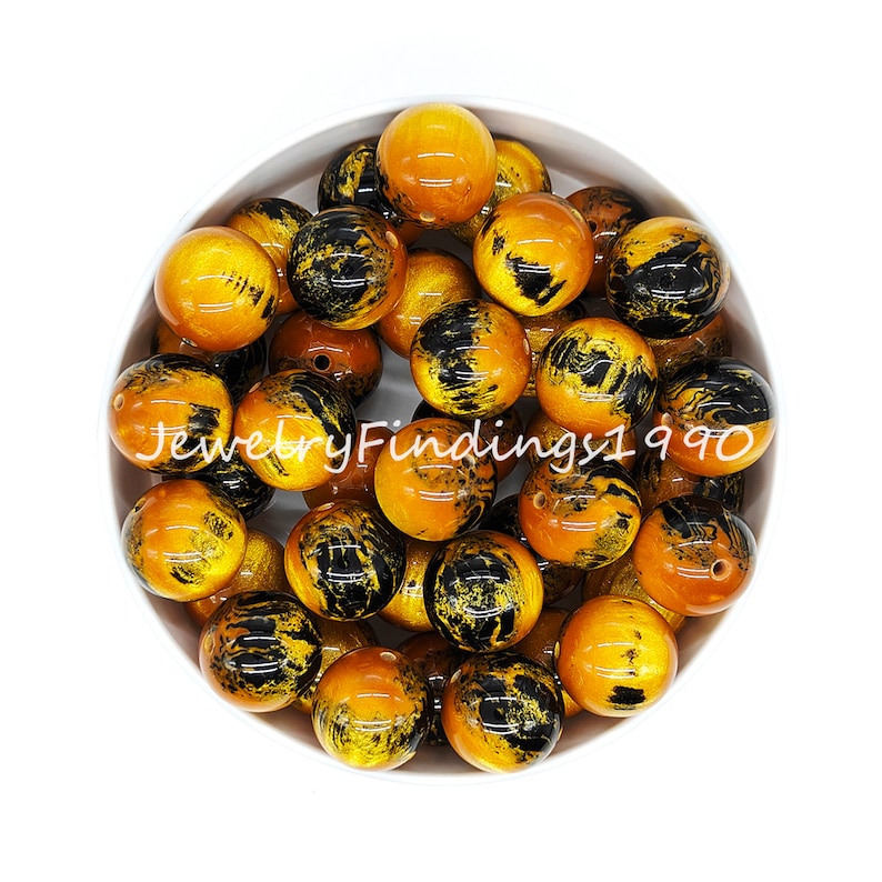 May include: A bowl of 20 round, yellow and black acrylic beads. The beads have a marbled effect with black swirls on a yellow background.
