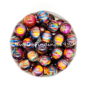 May include: A bowl filled with colorful iridescent round beads. The beads have a swirling pattern of blue, purple, gold, and red.