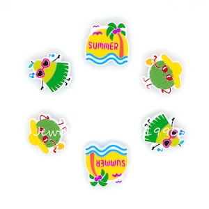 Peut inclure: Six charmes colorés sur le thème de l'été avec des personnages de dessins animés et le mot "SUMMER" sur deux des charmes.