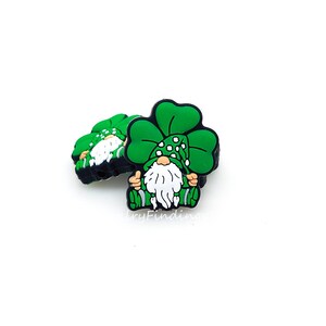 May include: Green shamrock charm with a gnome wearing a green hat with white polka dots. The gnome is sitting with its arms outstretched.