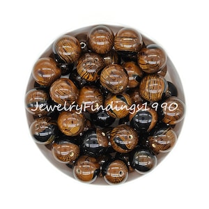 May include: A bowl of brown and black round beads with a wood grain pattern. The beads are approximately 20mm in diameter.