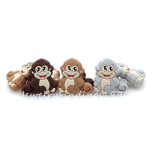 May include: A set of six brown, tan, and gray silicone monkey charms. The monkeys have smiling faces and are sitting with their tails curled behind them.