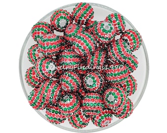May include: A bowl filled with red and green Christmas-themed beads. The beads are covered in sparkling rhinestones.