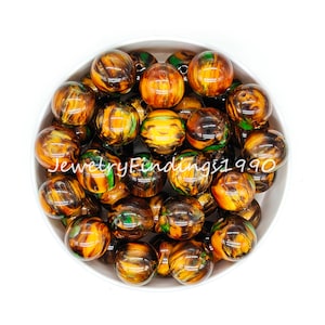 May include: A bowl of round, brown, green, and gold swirled acrylic beads. The beads are approximately 2 cm in diameter.